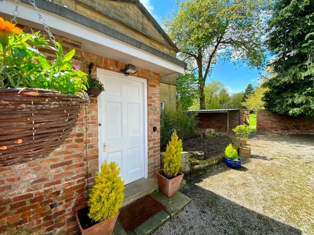 A cottage doorway and garden path framed by planting.