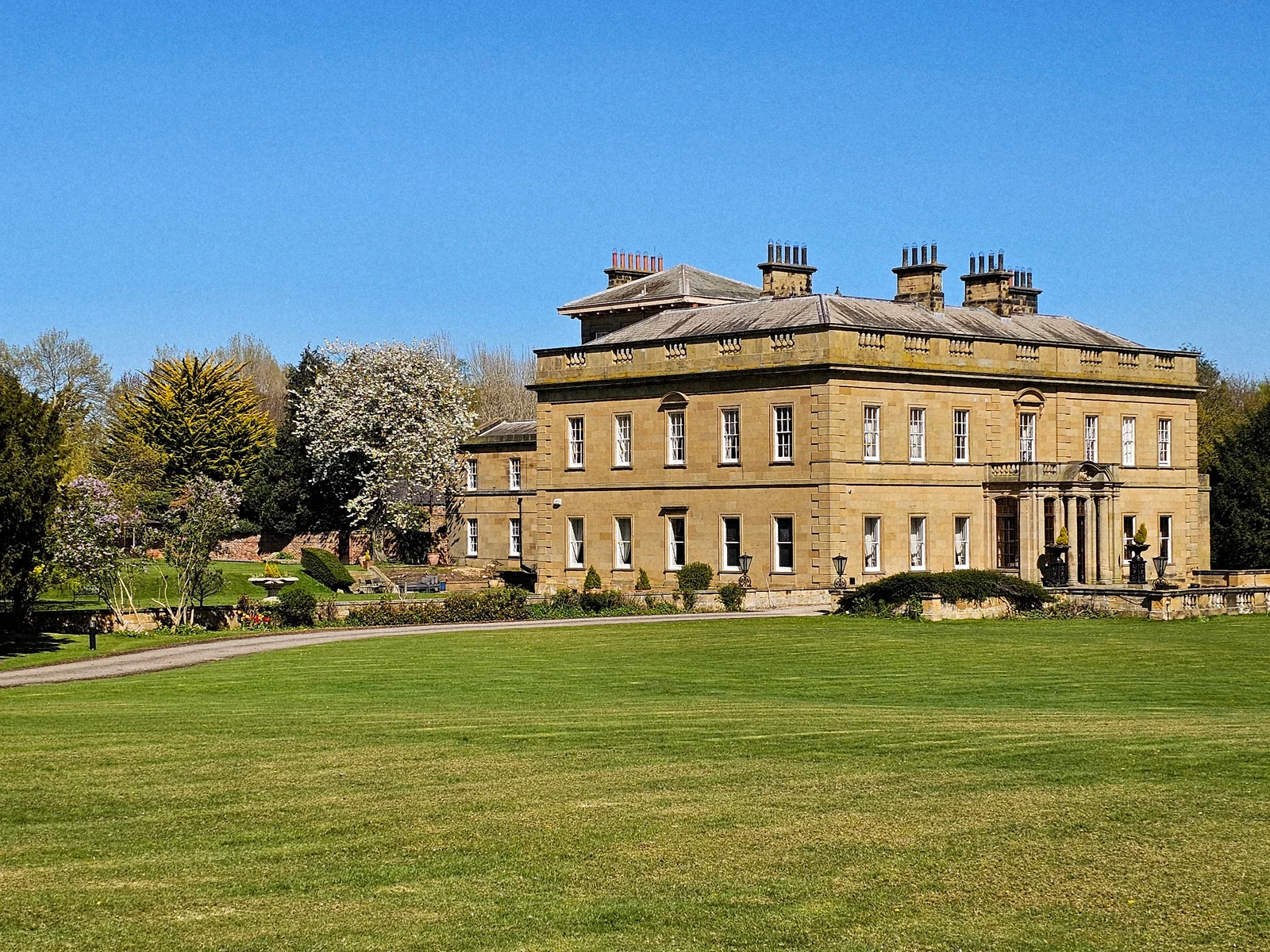 The stone frontage of Rudby Hall overlooking a green lawn.