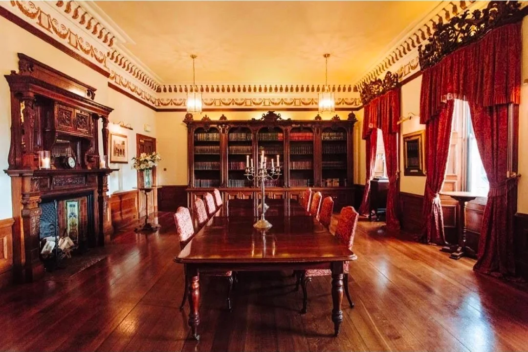 A long polished table and chairs in a richly decorated room at the Hall.