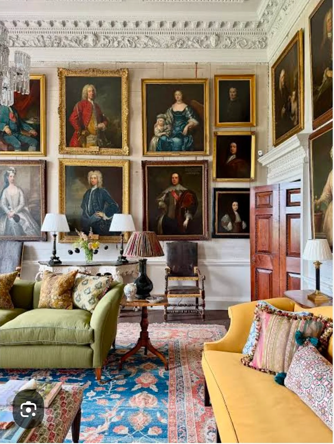A sitting room with period details, portraits and upholstered seating.