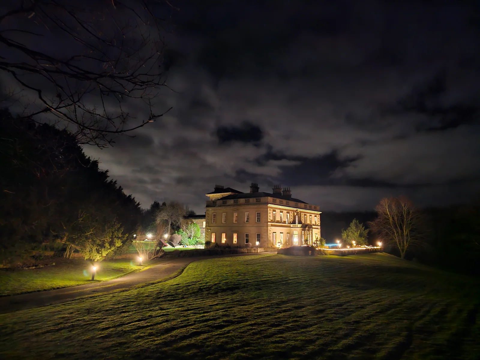 The Hall lit up at night with lawns in the foreground.